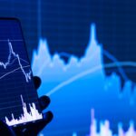 Close-up of a smartphone displaying a financial trading app with a graph on the screen against a dark blue background.